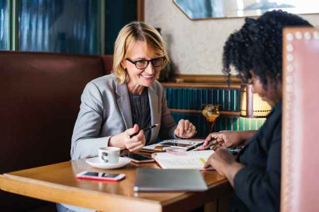 two woman sitting on bench near the table